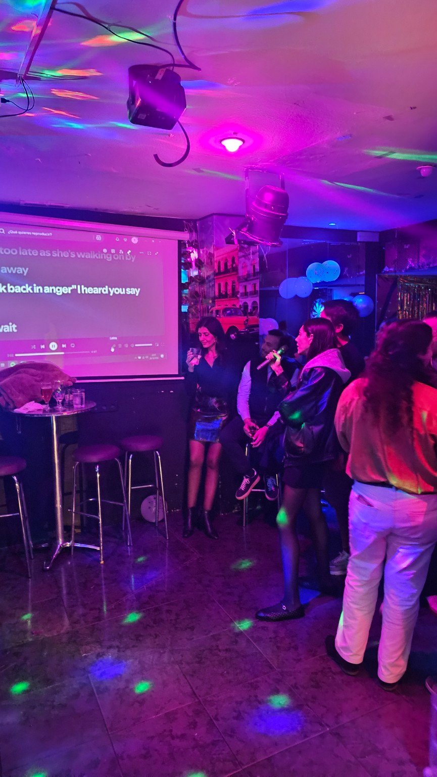 Invitados cantando con micrófonos y proyector durante una fiesta privada